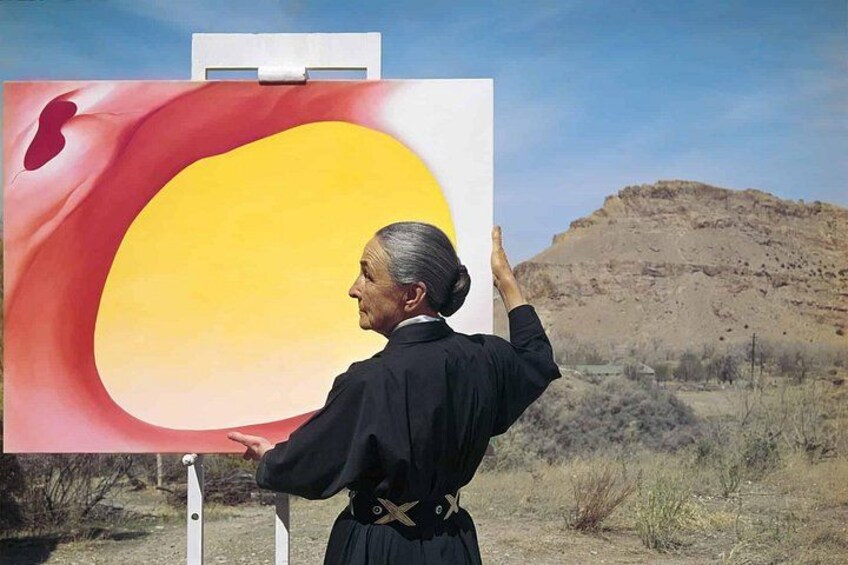 Una persona pinta un lienzo grande al aire libre, con un paisaje de fondo. 4