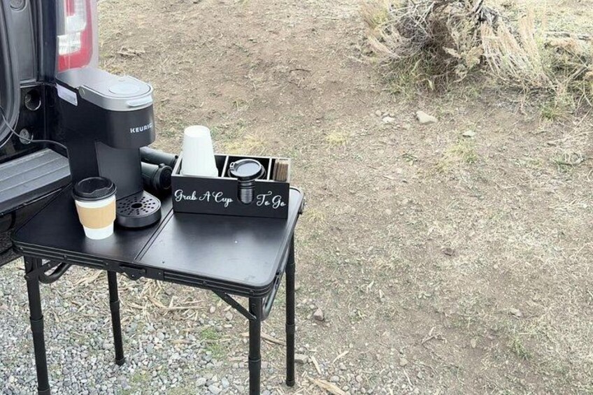 Ein tragbarer Kaffeezubereiter, eine Tasse und ein Tassenhalter auf einem Tisch im Freien. 3