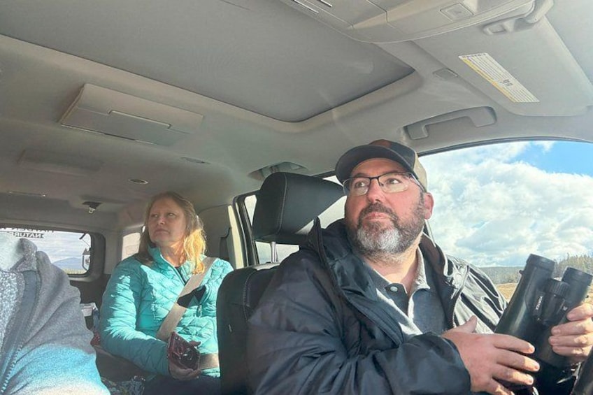 Two people in a vehicle with a landscape visible through the window. 2