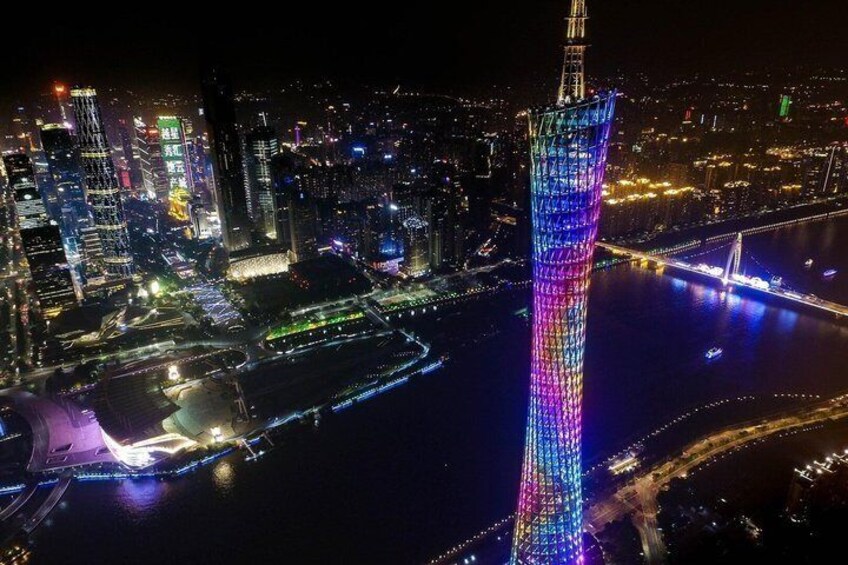 A cityscape at night with a prominent tower illuminated in a spectrum of colors. 3