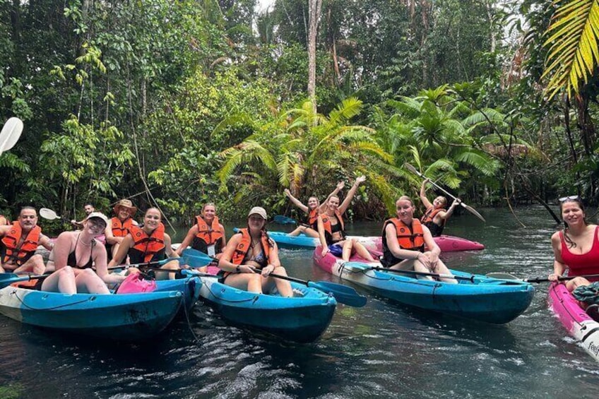 People in blue kayaks on a river surrounded by dense tropical vegetation. 3
