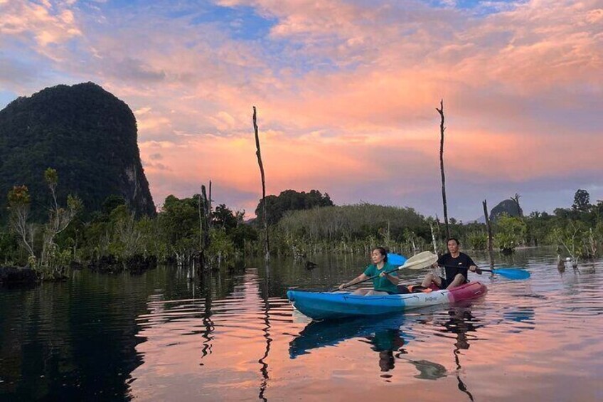 Two people kayaking on calm water with a mountainous landscape in the background. 1