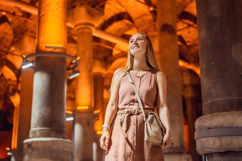 A person in a dress standing in a building with large columns and arches. 2