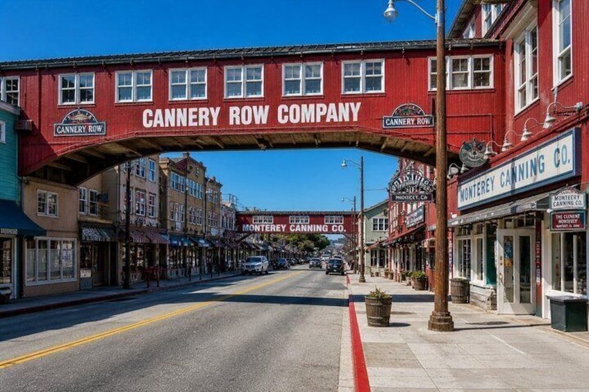 A street with a red archway labeled 'CANNERY ROW COMPANY' and storefronts. 3