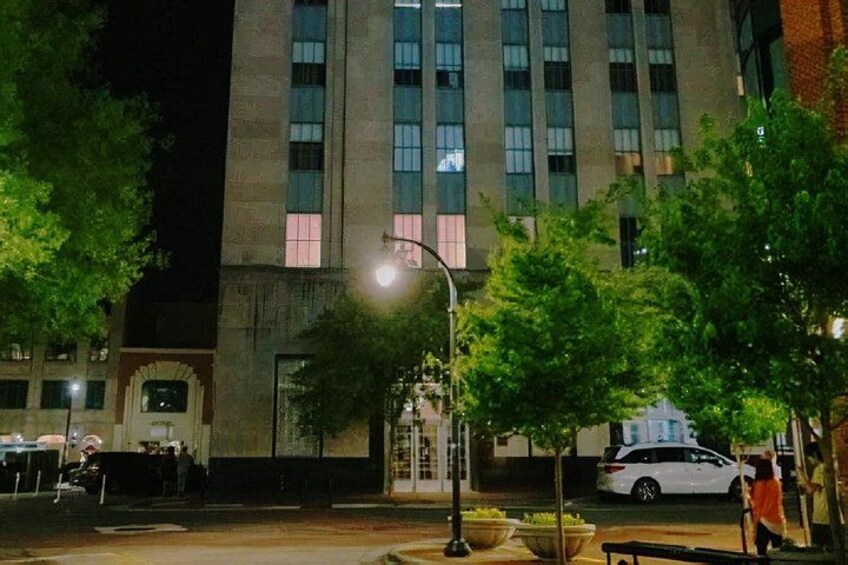 A nighttime urban scene with a building, street lamps, and a parked car. 2