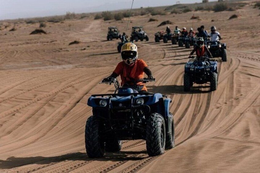 A group of people riding ATVs on a dirt road in a desert landscape. 4