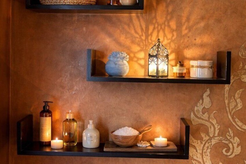 A wall with three shelves holding various toiletries and a candle. 4