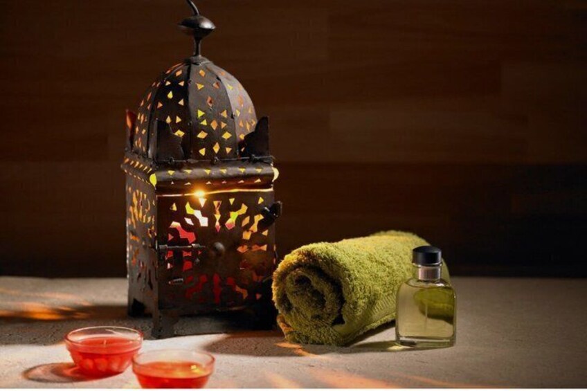 A decorative lantern, a rolled green towel, and a bottle of liquid. 2