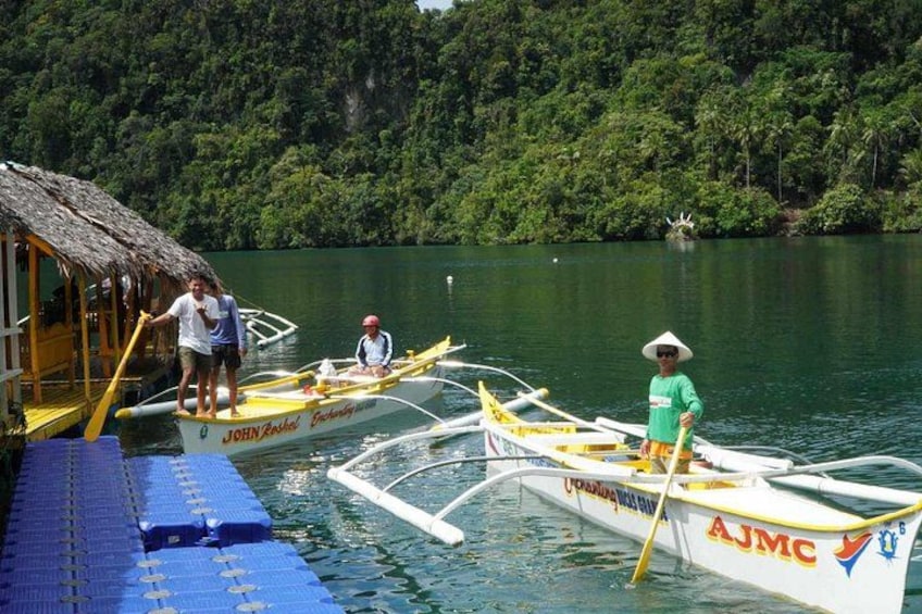 A lake with boats, a dock, and a thatched-roof structure. 4