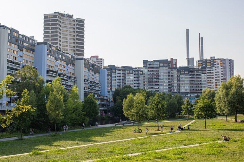 A park with green grass, trees, and people walking. 1