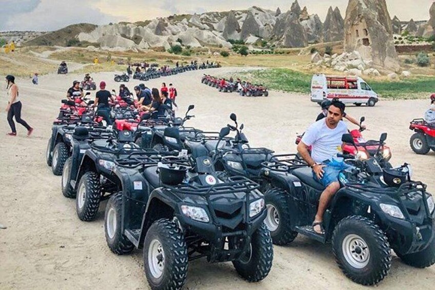A row of ATVs parked on a sandy beach with rocky formations in the background. 3
