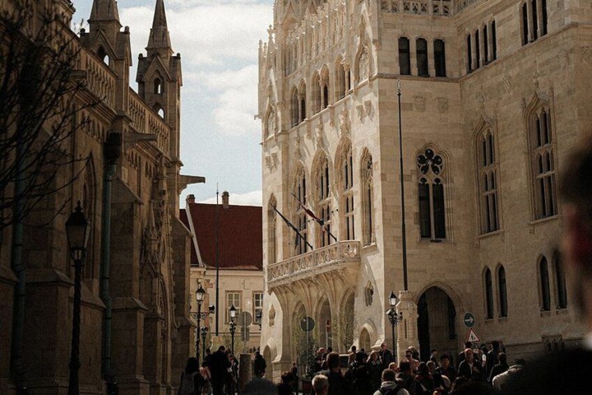 A historic building with ornate architecture, a crowd of people, and a street lamp. 5