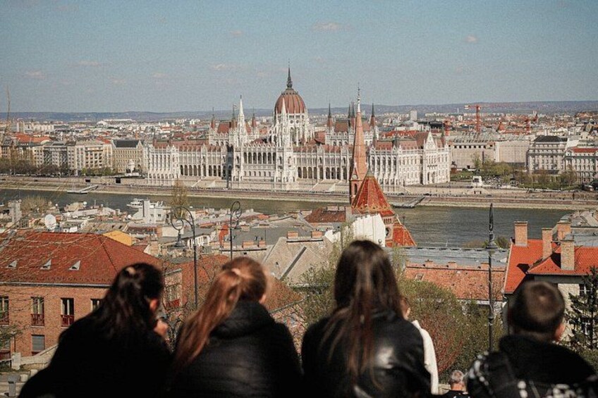 A group of people overlooking a cityscape with a prominent building with a dome and spires. 1