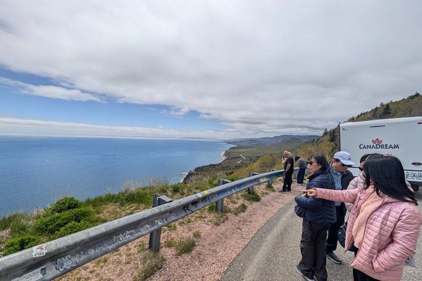 A coastal road with a guardrail, a truck labeled 'CANADREAM,' and people standing on the side. 2