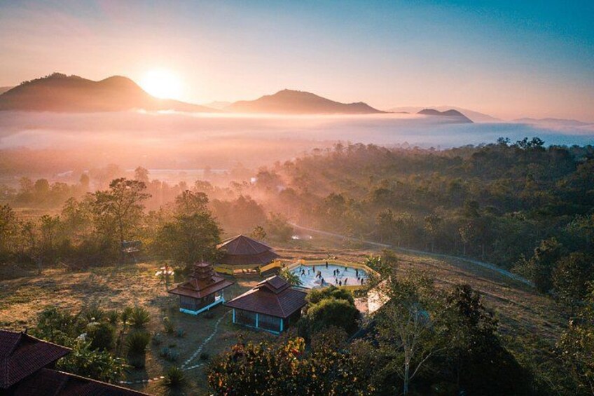 A sunrise over a mountainous landscape with a swimming pool and traditional buildings. 4