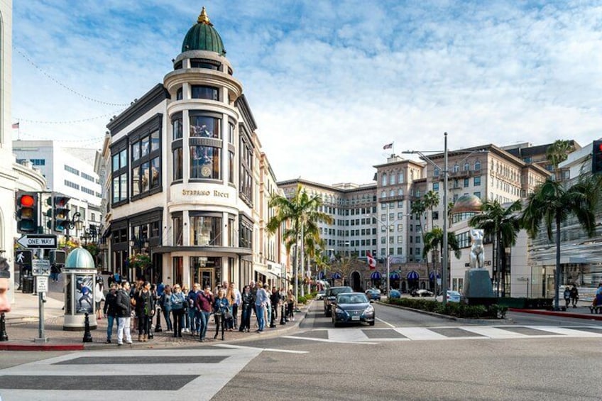 Une rue animée en milieu urbain, avec un bâtiment historique, des palmiers et un passage piéton. 5