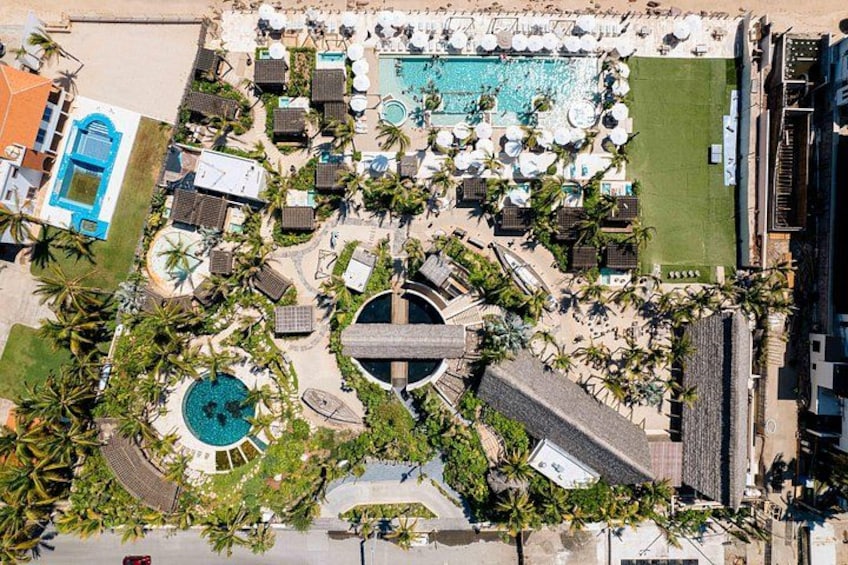 An aerial view of a resort with multiple swimming pools, lounge areas, and palm trees. 1