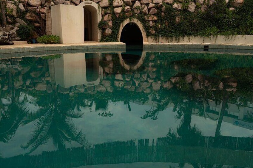 A swimming pool with a stone wall and a tunnel entrance. 5