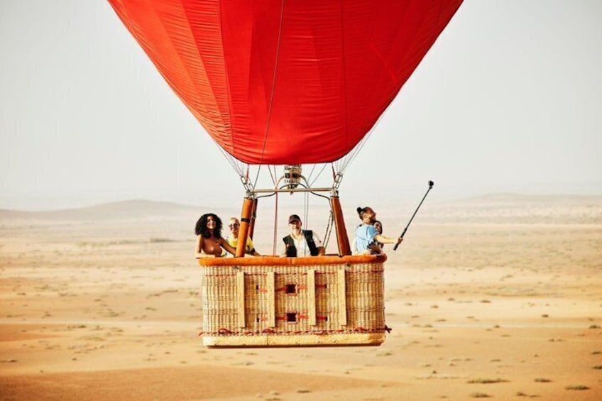 Een luchtballon met passagiers boven een woestijnlandschap. 1