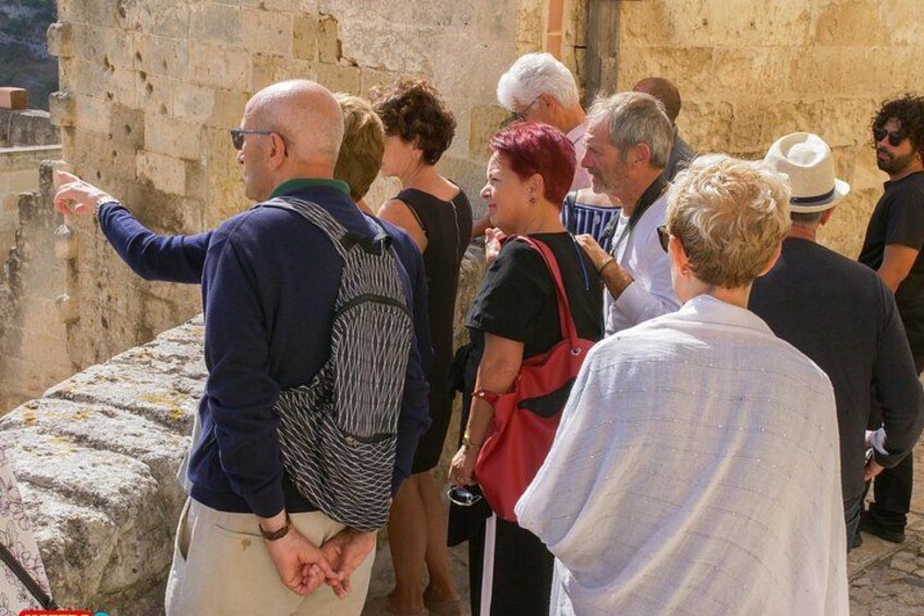 A group of people standing and observing a stone wall. 3