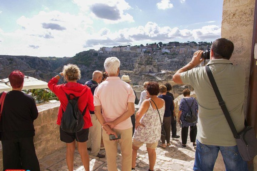 A group of people taking a photo of a cityscape from a stone platform. 3