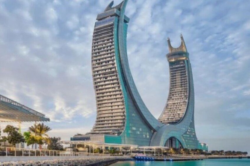 A modern architectural structure with two curved towers, a waterfront, and a clear sky. 2
