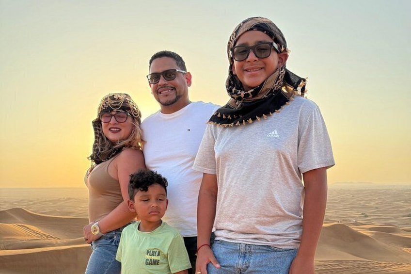 En familj på fyra personer står på en strand med sanddyner i bakgrunden. 5