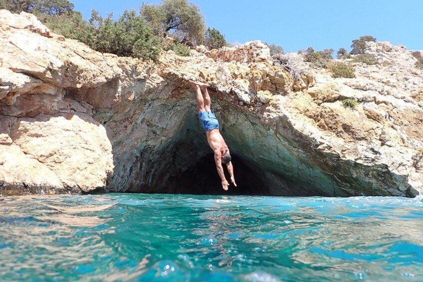 Una persona se sumerge en una piscina azul cristalina desde una cueva rocosa. 4