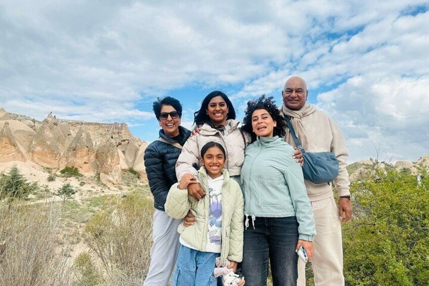 A family of five standing in a natural landscape with rocky formations and sparse vegetation. 2