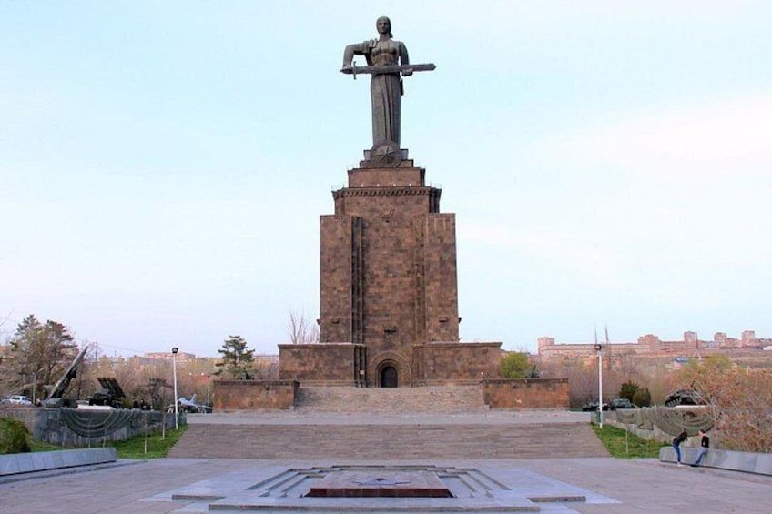 A statue on a pedestal with a brick base, surrounded by a paved area with steps leading up to it. 2