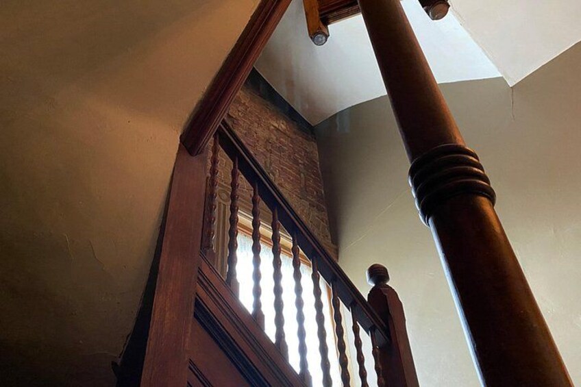 A wooden staircase with a balustrade, a brick wall, and a white ceiling. 3