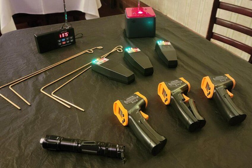 A table with various electronic devices, including a digital clock, a power strip, and several black and yellow tools. 2