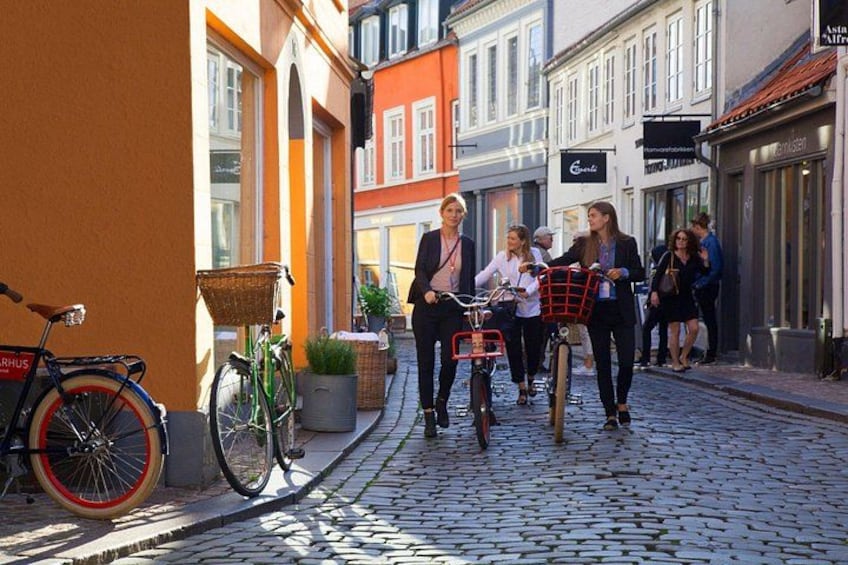 A cobblestone street with bicycles, a basket, and people walking. 1