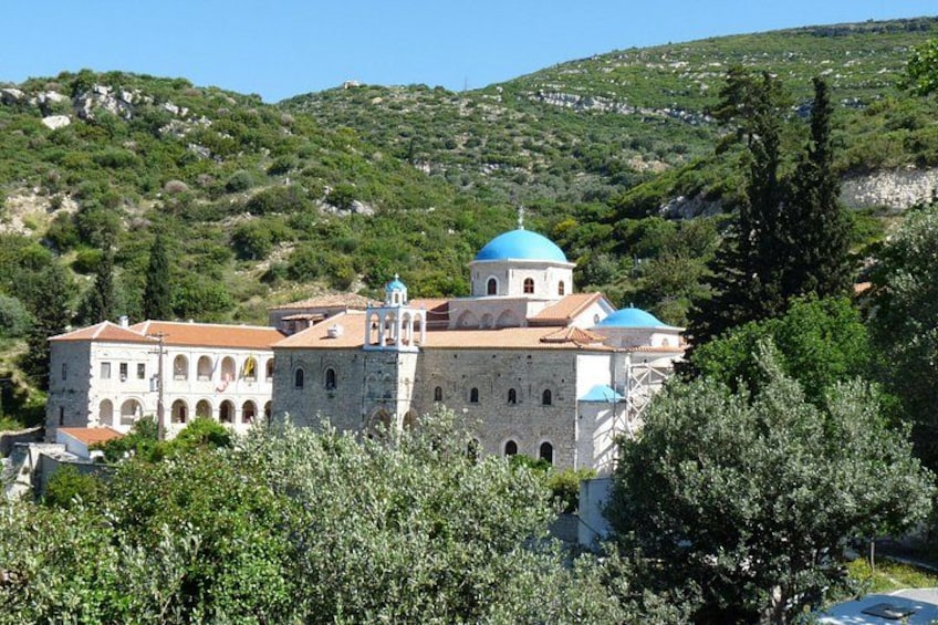 A historic building with a prominent dome and arched windows, surrounded by lush greenery and hills. 2