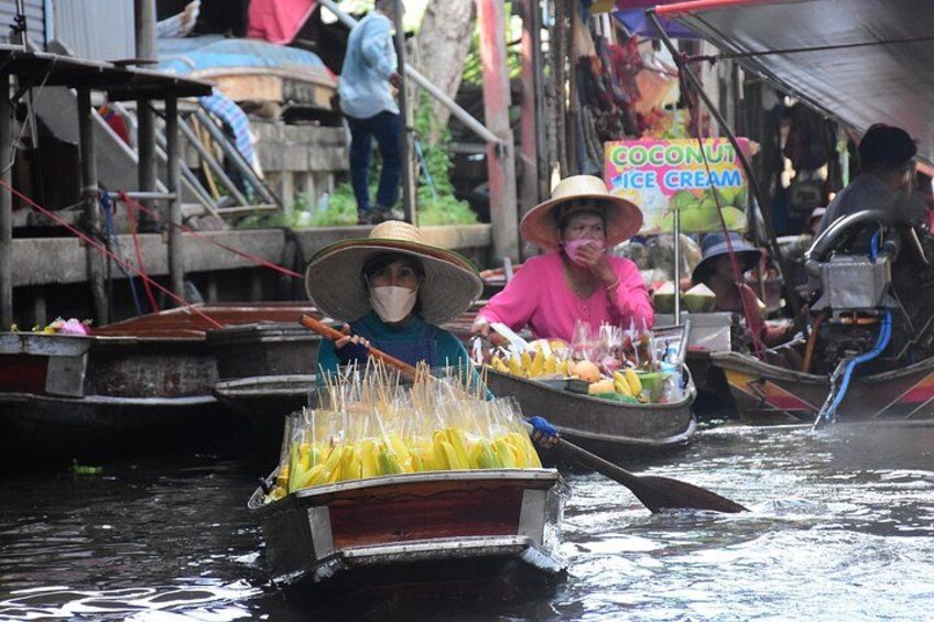A person in a boat carrying yellow fruits, another person in a pink shirt, and a sign for coconut ice cream. 2