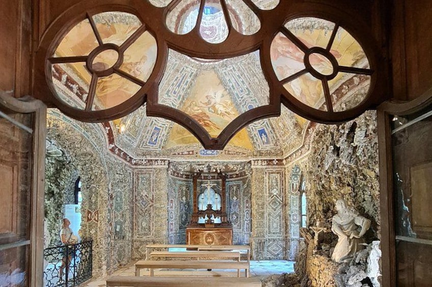An ornate interior with a central altar, intricate wall decorations, and a statue. 2