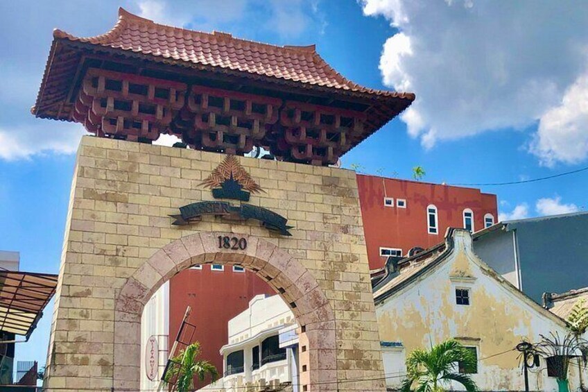 A historical archway with the year 1820, a tiled roof, and a building in the background. 3