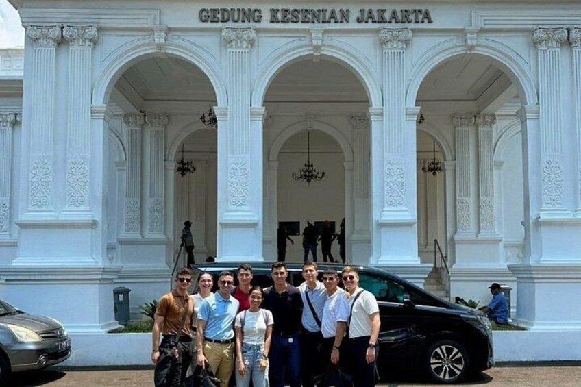 A group of people in front of Gedung Kesenian Jakarta, a white building with arches and columns. 1