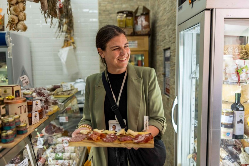A person holding a tray of cured meats in a deli. 1