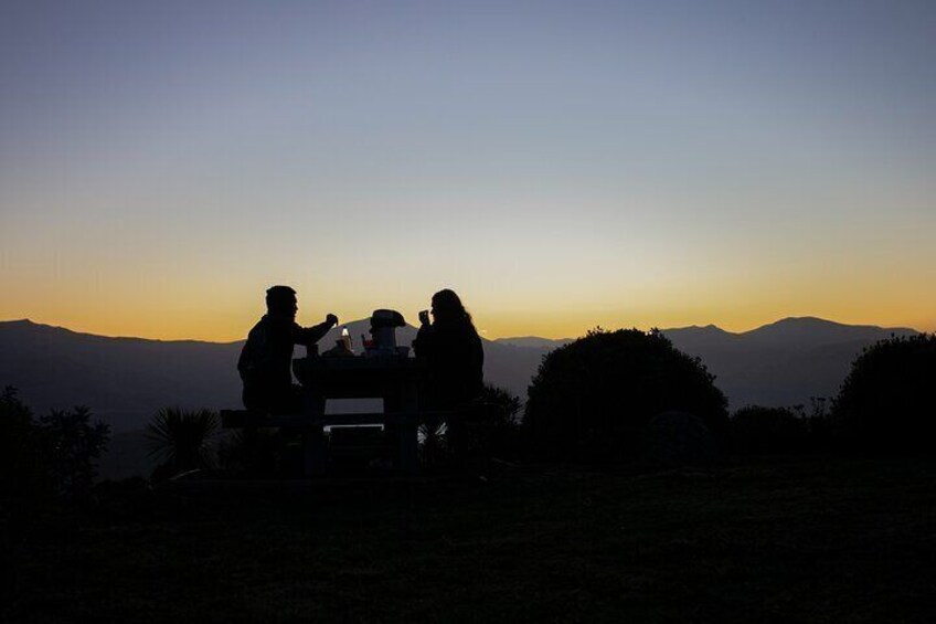 Two people sitting at a table with a view of mountains during sunset. 1