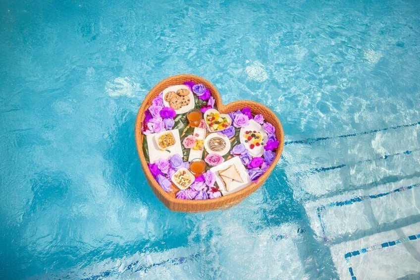 A heart-shaped basket filled with food and flowers floating in a pool. 5
