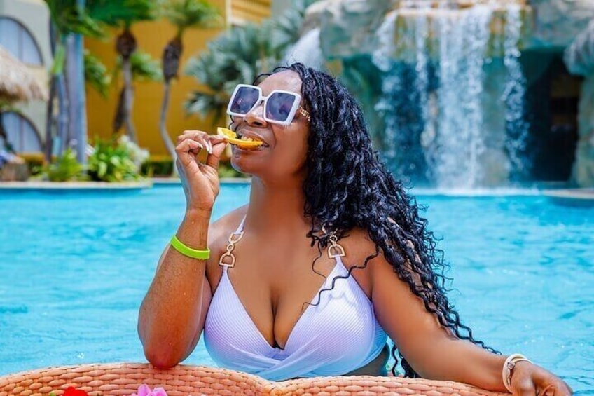 A person in a white bikini at a pool with a waterfall in the background. 2