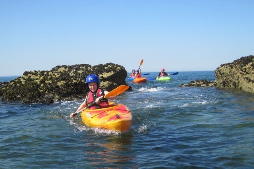 Personas haciendo kayak en un mar tranquilo con afloramientos rocosos. 1