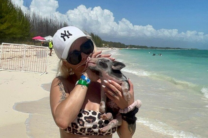 Una persona sostiene un animal pequeño en una playa con cielos despejados y aguas tranquilas. 3