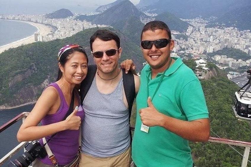 Three people standing with a scenic city and mountains in the background. 1