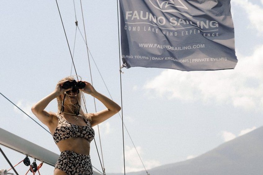 Een persoon op een zeilboot met een vlag waarop 'FAUNO SAILING' staat en een websiteadres. 4