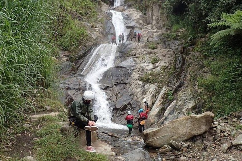 A waterfall with people standing on a rocky slope. 2