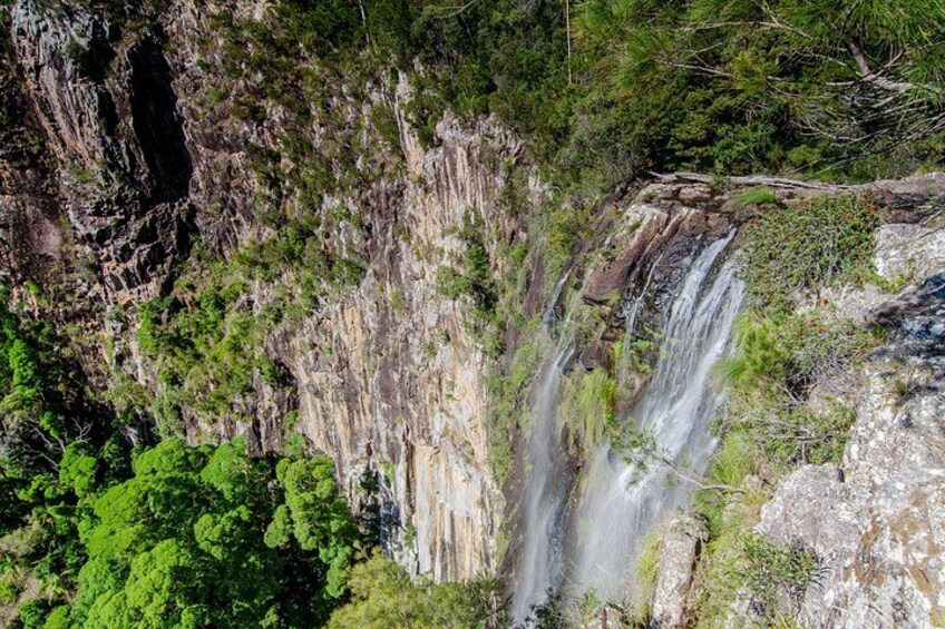 A waterfall cascading down a rocky cliff surrounded by dense green foliage. 3