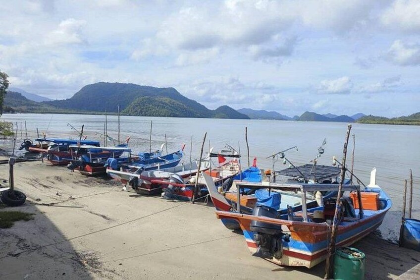 A row of small boats docked at a pier with a mountainous landscape in the background. 2