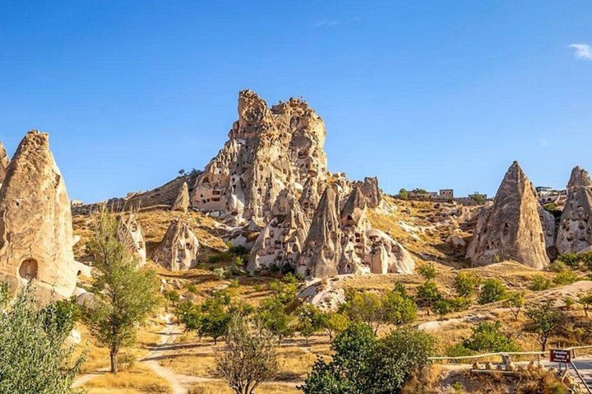 A landscape with prominent rock formations, a clear sky, and sparse vegetation. 1